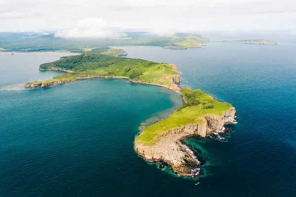 Tobizina Burnu 'nun hava manzarası, Vladivostok yakınlarındaki Russky Adası. Mavi deniz kıyısındaki yeşil orman, kayalık ve sarp kayalıklar, güneşli bir yaz günü. Primorsky Krai, Uzak Doğu, Rusya 'da deniz manzarası
