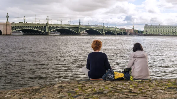 Deux filles sur la rive de la Neva regardent le pont de la Trinité à — Photo