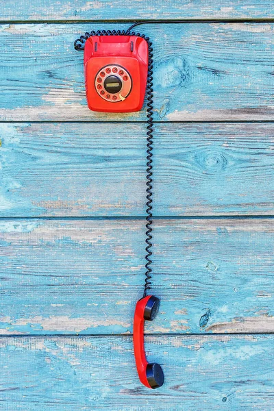 Red retro telephone on the background of old boards