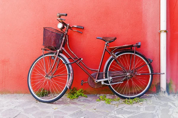 Old bicycle on a red wall background — Stock Photo, Image