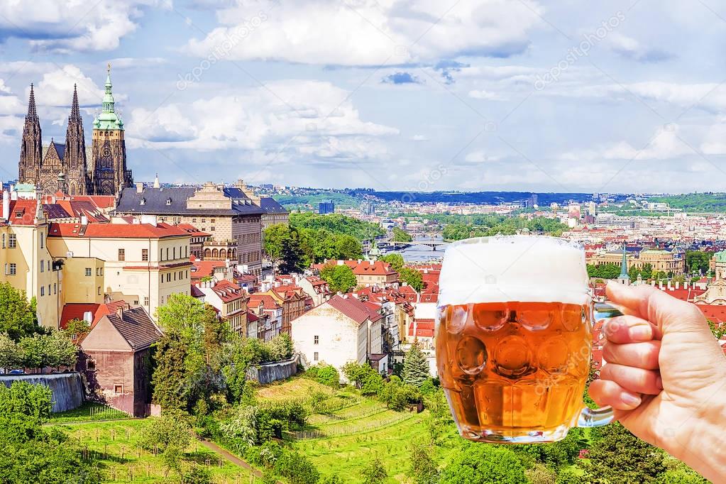 Hand with a mug of beer on the background of the panorama of Pra