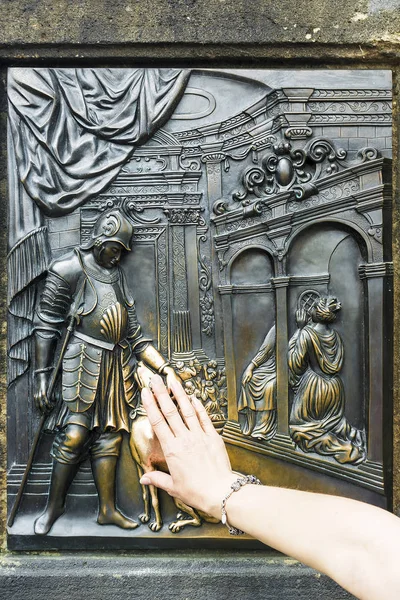 O turista esfrega a placa memorial de bronze de São João de Nepomuk — Fotografia de Stock