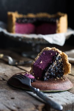 Koyu arkaplanda yabanmersinli cheesecake  