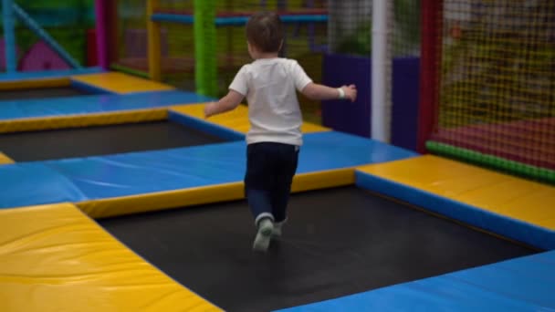 Niño Descansando Sala Juegos Corriendo Camas Elásticas Disparando Por Espalda — Vídeo de stock