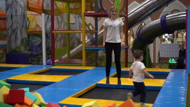 Woman White Shirt Black Trousers Jumps Trampolines Small Boy Runs — Stock Video