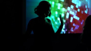  Moskova / Rusya - 12.24.2019: Arka planda disko topu, şirket, kulüp partisi, yavaş çekim ile bir gece kulübünde dans eden ve şarkı söyleyen kadın silueti