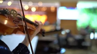 Kahverengi saçlı bir kadın, mavi gece elbisesi ve pulları olan, keman çalan, yandan çekim yapan, yavaş çekim yapan