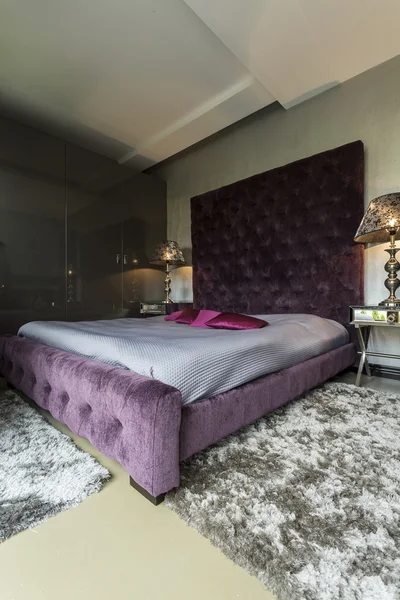 Groot bed met paarse kussens — Stockfoto
