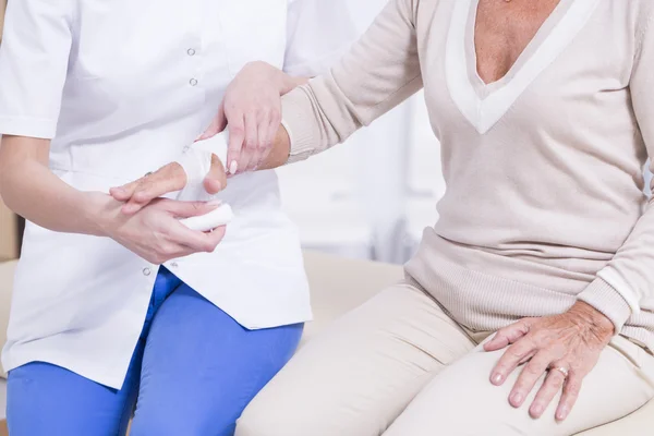 Sjuksköterska att sätta bandaget på kvinnas hand — Stockfoto