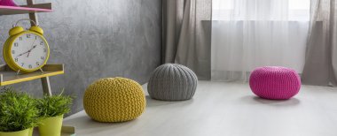 Gri bir odada renkli poufs