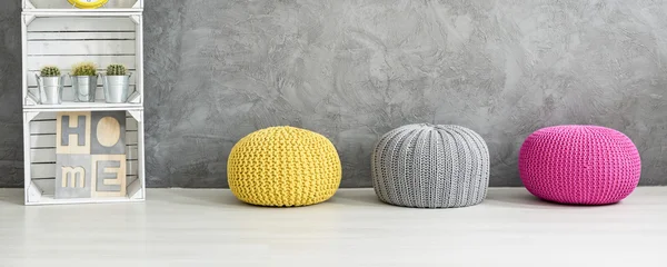 Colorful poufs and a shelf against a grey wall — Stockfoto