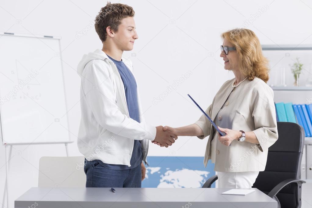 Female teacher shaking student hand