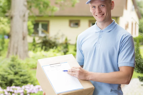 Courier holding a parcel and a clipboard — Stock Photo, Image