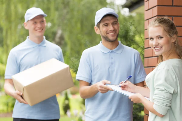 Couriers and content woman signing a form — Stock Photo, Image