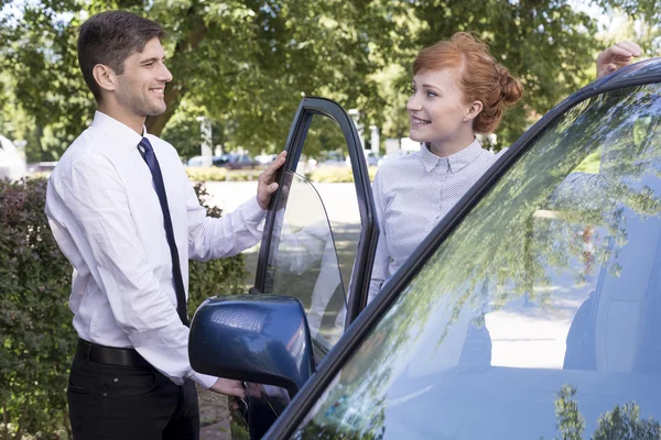 Un homme ouvre la porte d'une voiture à une femme d'affaires — Photo