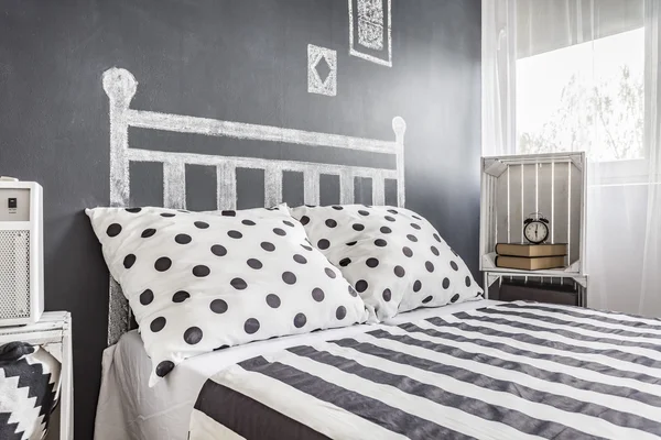 Bed in a black and white with a chalkboard wall — Stock Photo, Image