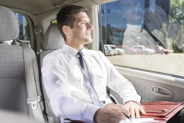 Businessman sitting on a backseat in a taxi — Stock Photo, Image