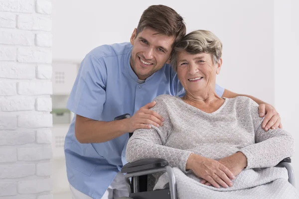 Enfermeira masculina abraçando sua paciente idosa — Fotografia de Stock