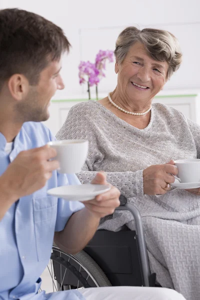 Donna anziana bere il tè con il suo caregiver — Foto Stock