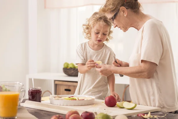 Child helping grandmother with baking — Stock Photo, Image