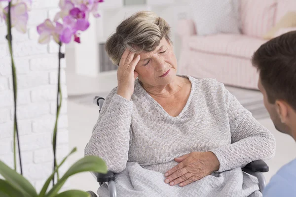 Anciana en silla de ruedas con dolor de cabeza — Foto de Stock