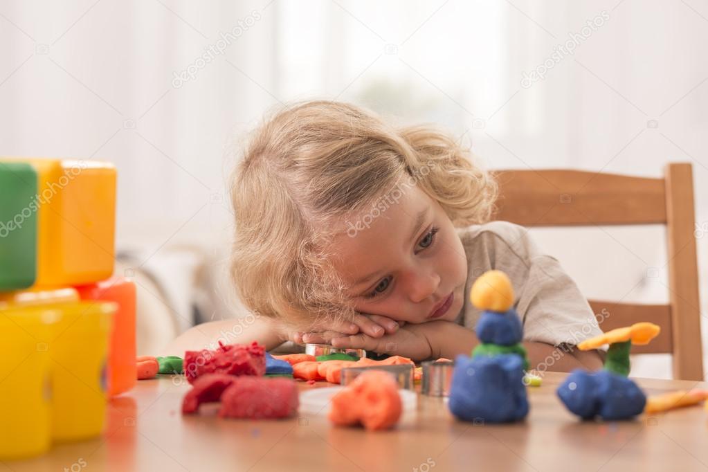 Bored girl with plasticine toys