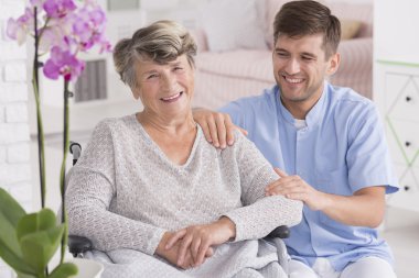 Hemşire kadın yanında tekerlekli sandalye üzerinde oturan gülümseyen 