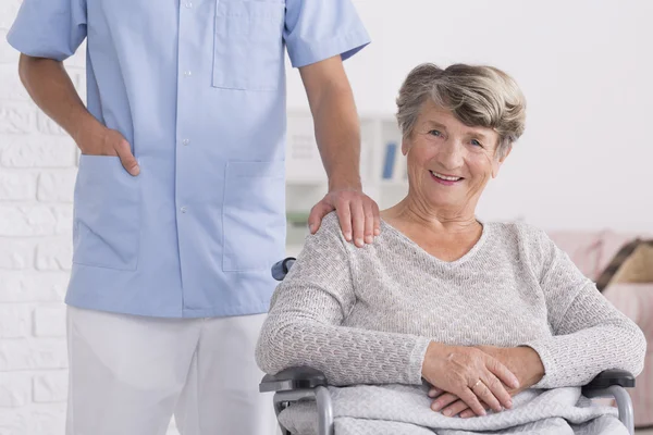Caregiver ve tekerlekli sandalye kadının omzuna bir el ile — Stok fotoğraf