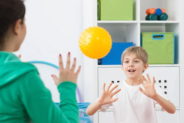 Menino jogando bola com fisioterapeuta — Fotografia de Stock