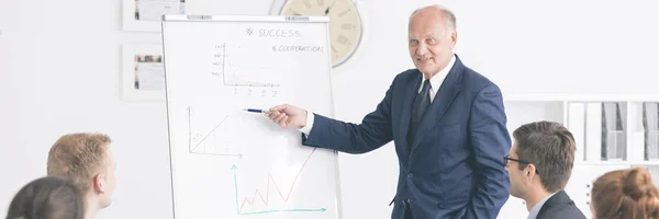 Man making a presentation close to the board with charts — Stock Photo, Image