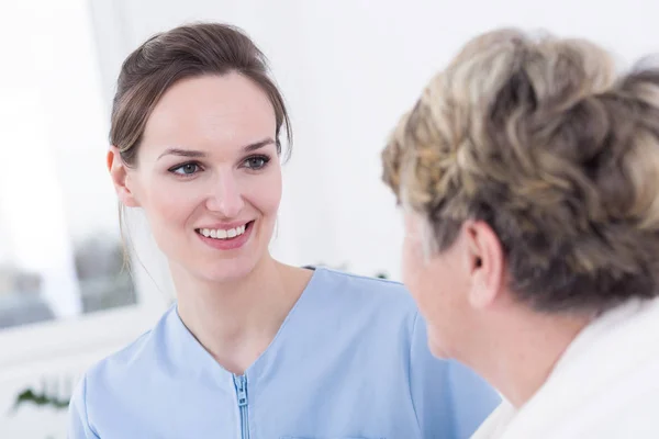 Infermiera sorridente alla donna più anziana — Foto Stock