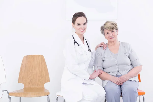 Dokter zittend op een stoel dicht bij haar senior patiënt — Stockfoto
