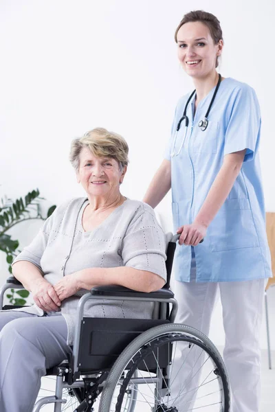 Hemşire ve kadın bir tekerlekli sandalye üzerinde — Stok fotoğraf