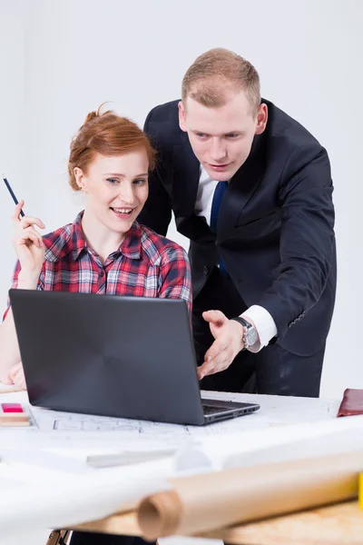 Womanand homem sentado perto da placa de elaboração na frente do laptop — Fotografia de Stock