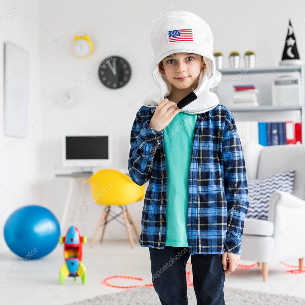 Boy standing in his room and wearing a toy space helmet