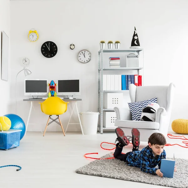 Niño leyendo un libro en su dormitorio — Foto de Stock