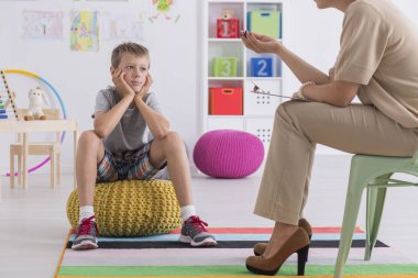 Bir psikoterapist ile konuşurken bir kabarık üzerinde oturan çocuk