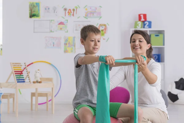 Fizyoterapist ve bir spor salonu topa oturan çocuk — Stok fotoğraf