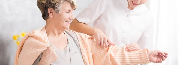 Enfermera joven ayudando a anciana — Foto de Stock