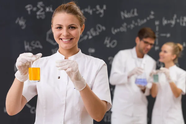 Científico sosteniendo una cristalería de laboratorio con líquido naranja — Foto de Stock