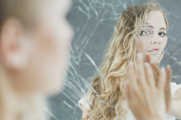 Женщина касается своего зеркального отражения
