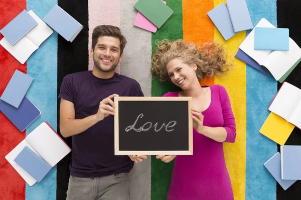 Mutlu çift balcboard 'aşk' kelime ile tutarak — Stok fotoğraf
