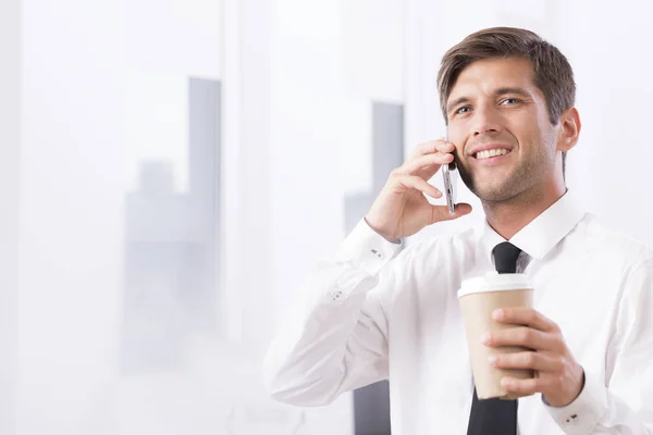 Mitarbeiter unterhält sich am Handy mit Kaffee — Stockfoto