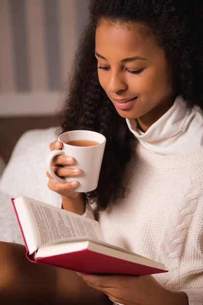 Mujer leyendo un libro y sosteniendo una taza —  Fotos de Stock