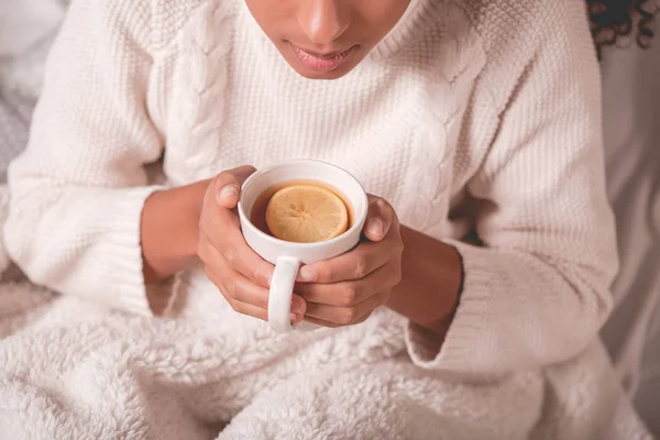 Kvinnan bär en vit tröja och håller en mugg te — Stockfoto