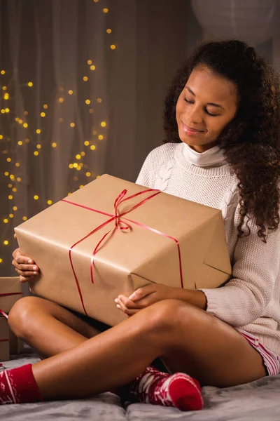 Femme regardant un gros cadeau sur ses genoux — Photo