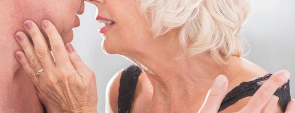Bejaarde vrouw in lingerie kussen man — Stockfoto