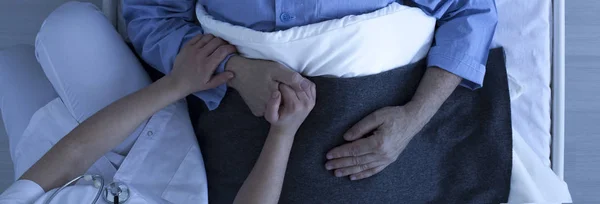 Медсестра держит пожилого мужчину за руку — стоковое фото