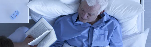 Čtení pro starší nemocný muž pečovatele — Stock fotografie