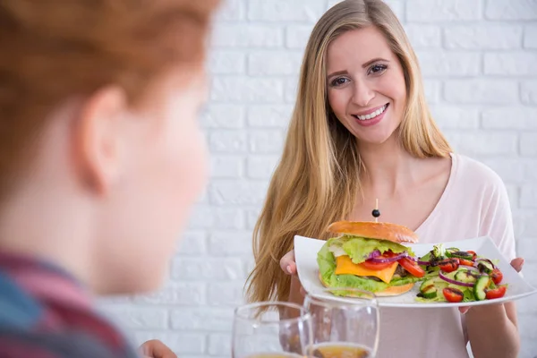 Femme tenant cheeseburger avec salade — Photo